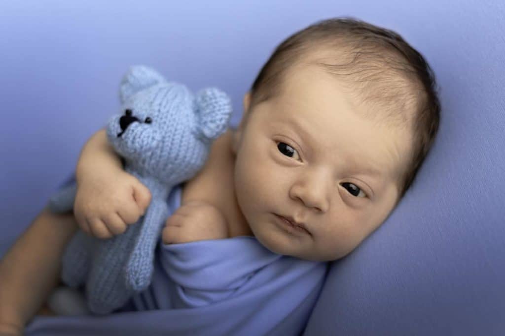 A newborn baby posing on blue background