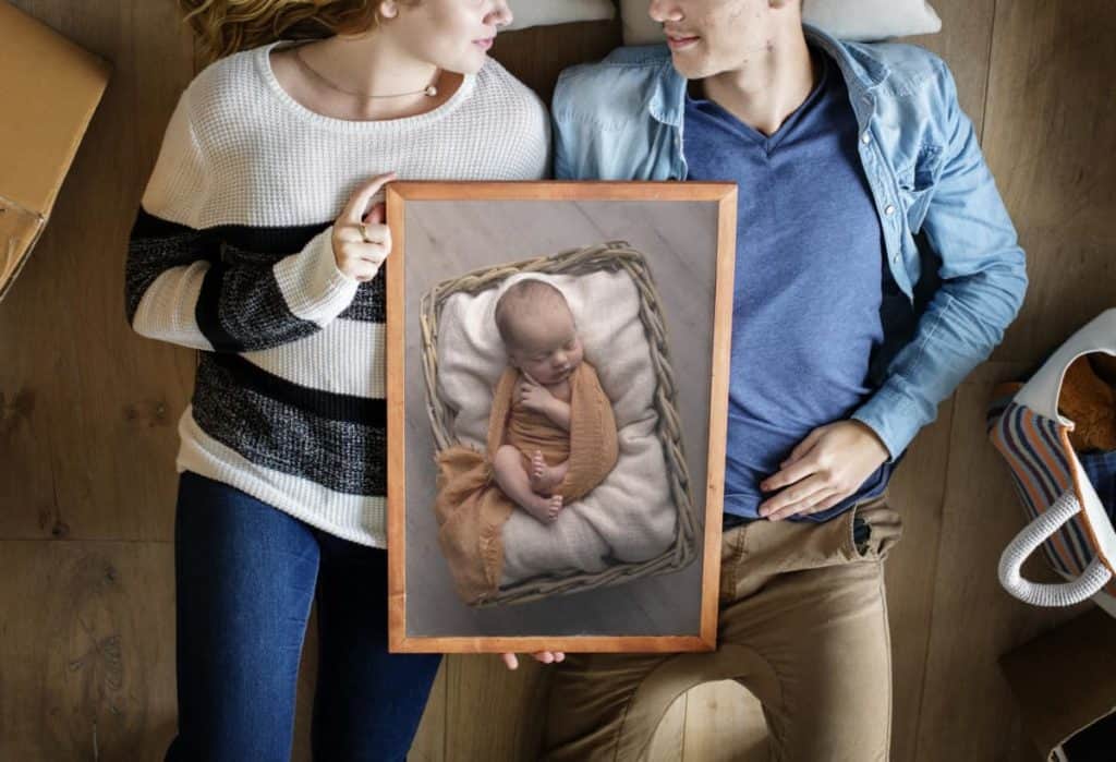 A couple with the framed picture of their newborn baby