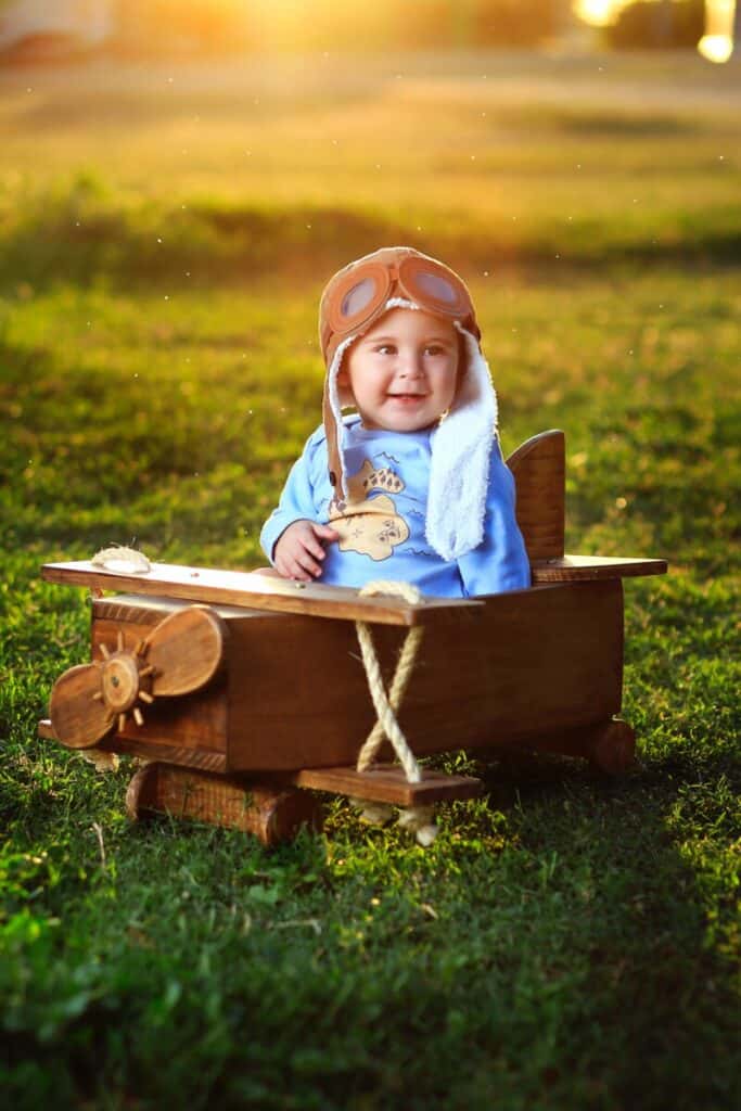 Baby boy posing ina wooden plane prop