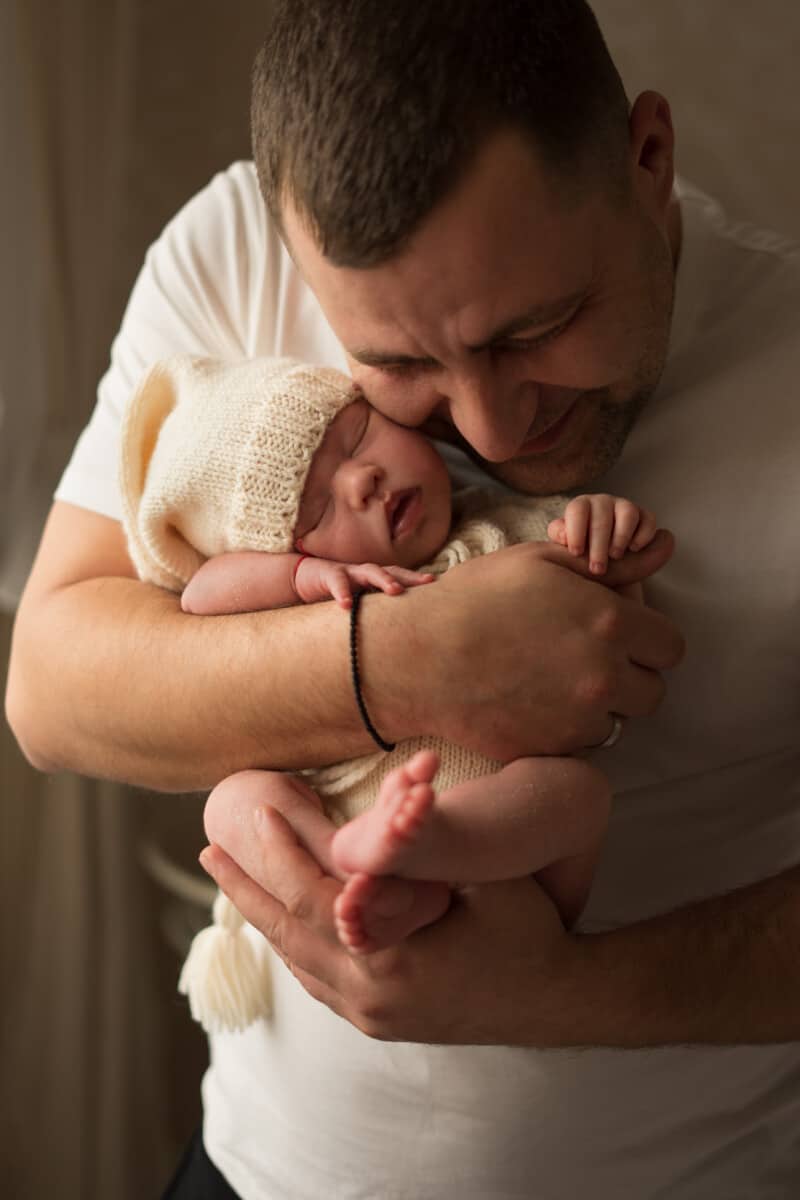 Young Dad holding his new-born baby during photo shoot